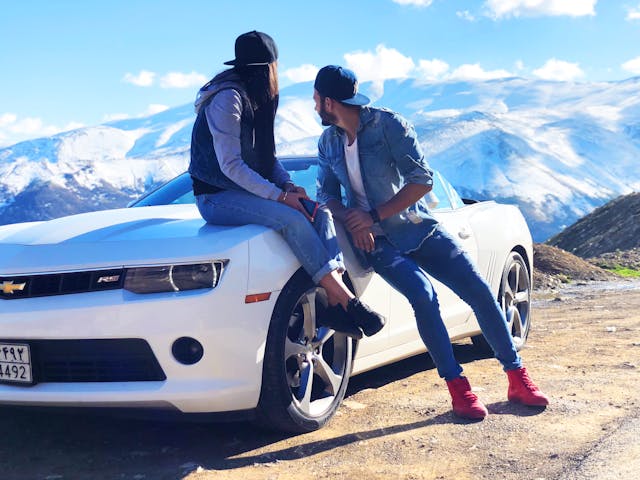 Two travelers standing beside their car on a road trip stop